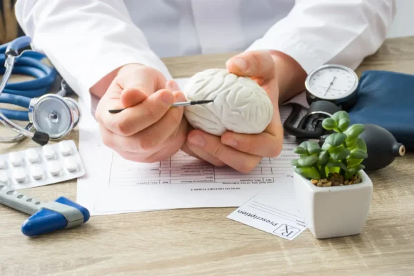 A doctor holds a brain model on a table, illustrating the link between infections and neuropsychiatric symptoms.