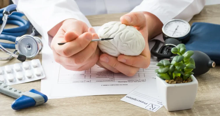 A doctor holds a brain model on a table, illustrating the link between infections and neuropsychiatric symptoms.