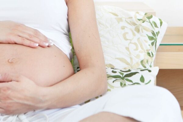 A pregnant woman sitting on a couch, reflecting on the benefits of acupuncture during pregnancy for prenatal health.