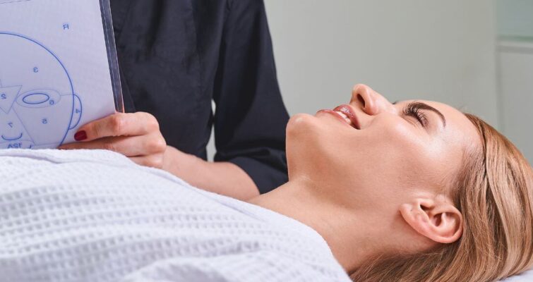 A woman receives a facial treatment in a serene room, highlighting the practice of Face Mapping in Chinese Medicine.