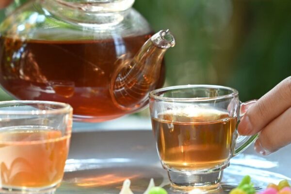 A person pours tea into two glasses, highlighting the theme of hormone balancing with the best teas.