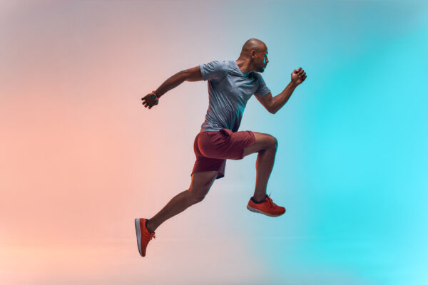 A man in a running pose against a vibrant background, symbolizing energy and vitality related to low testosterone treatment.