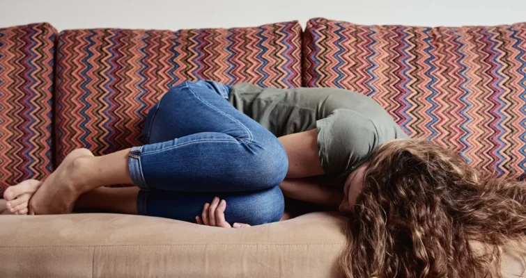 A woman peacefully sleeps on a couch, highlighting the importance of rest in managing endometriosis and GI health.