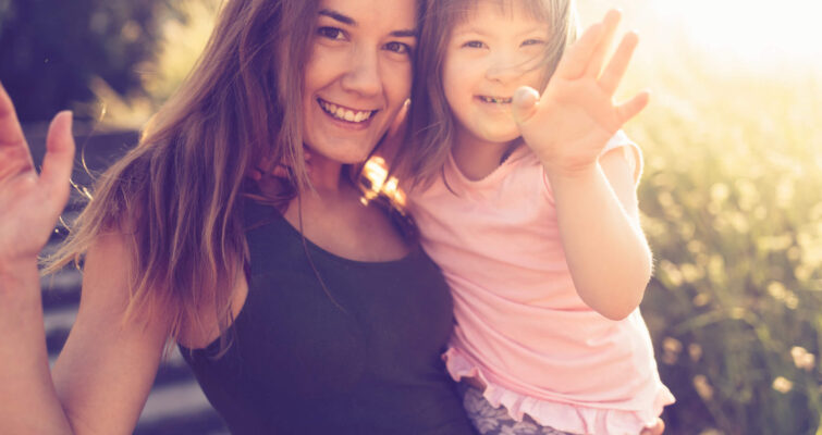 A woman joyfully lifts a little girl into the air, symbolizing love and connection in the context of MTHFR in children