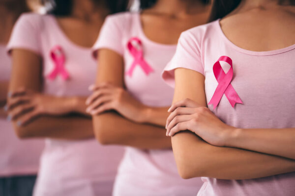 Women holding pink ribbons for breast cancer awareness, emphasizing healthy estrogen levels to reduce risk.