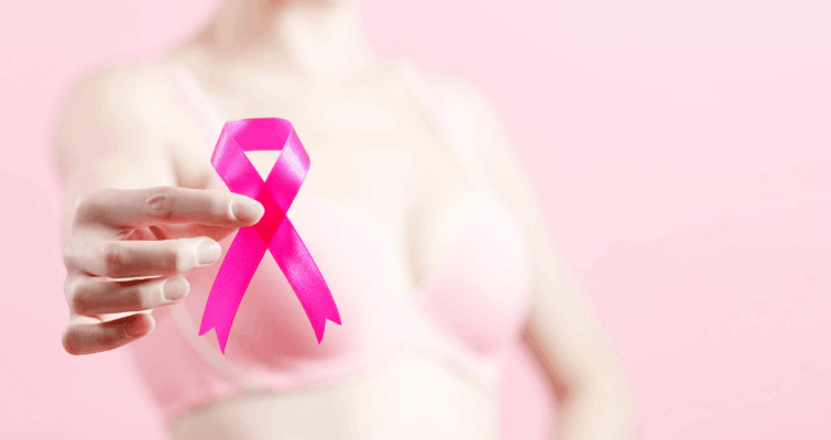 A woman in a bra holds a pink ribbon, symbolizing breast cancer awareness and prevention through functional medicine.