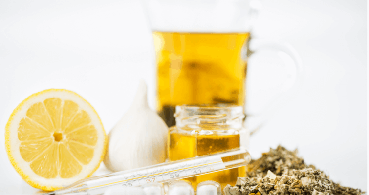 A glass of tea with lemon and pills, representing immune supplements for cold and flu season preparation.