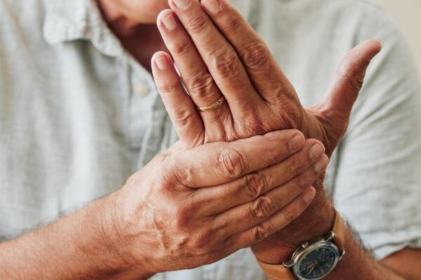 A man with arthritis holds his hands to his face, expressing discomfort related to osteomalacia and osteoporosis differences.