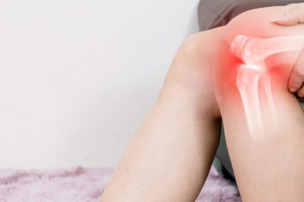 A woman holding her knee, indicating pain, with a focus on issues related to osteoporosis and arthritis.