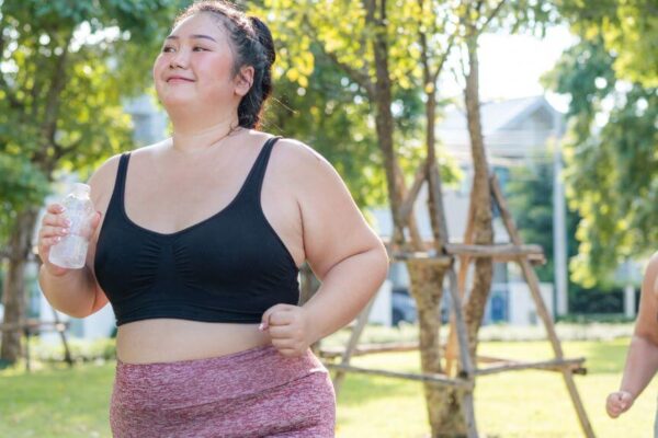 Two women in sports bras running together in a park, promoting fitness and well-being.