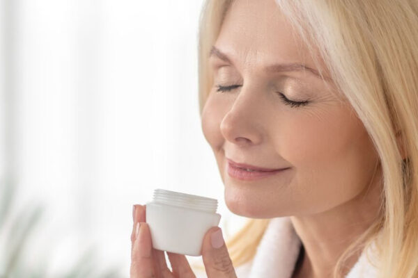 A woman holds a white container, emphasizing skin care for women over 40 in a beauty context.