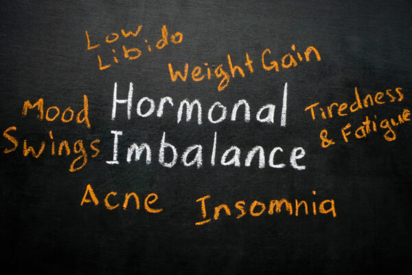"Hormonal Imbalance" written on a chalkboard with symptoms listed around it