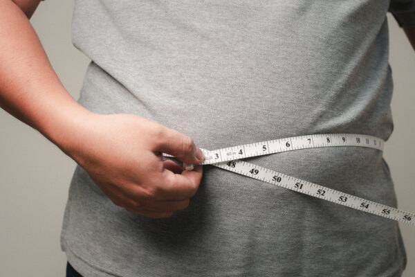 Overweight man measuring his waistline