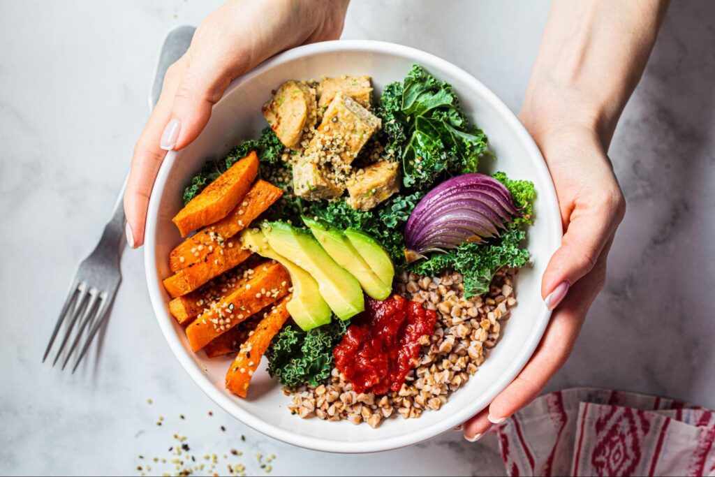 Hands holding a bowl of healthy salad