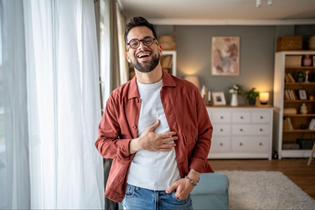 A smiling man holding his stomach