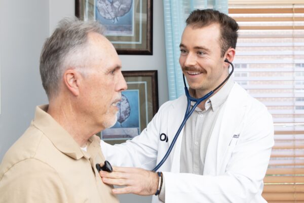 functional medicine doctor performing a men's health exam on patient in exam room