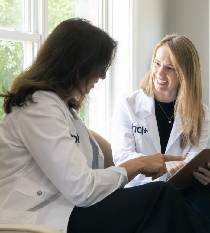 two hol+ functional medicine doctors discussing women's health with a clipboard