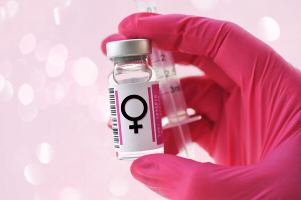 A vial of Hormone Replacement Therapy on a pink background for breast cancer awareness