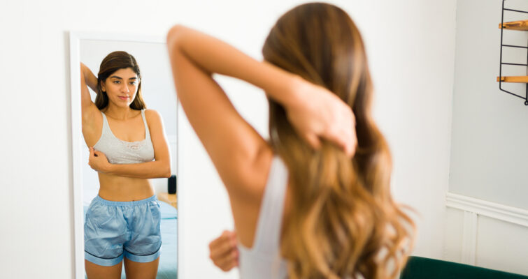 young woman doing a self breast exam for breast cancer