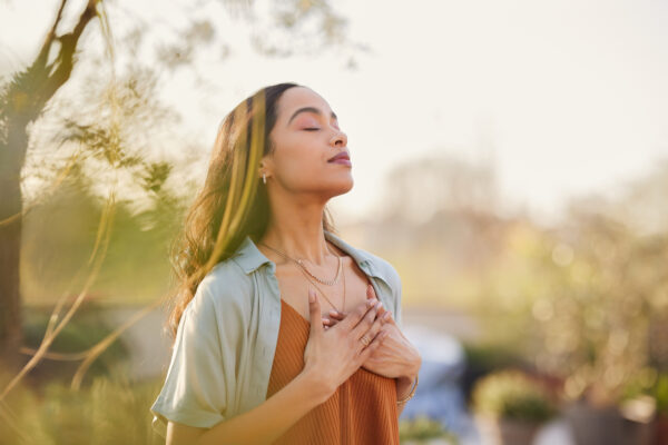 Young woman with hand on chest breathing in fresh air.
