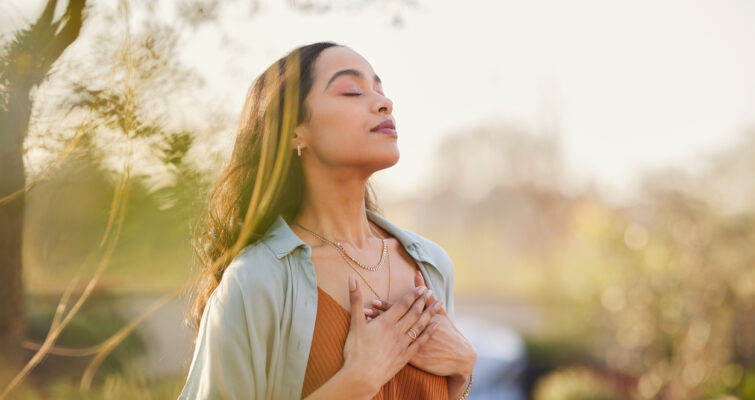 Young woman with hand on chest breathing in fresh air.