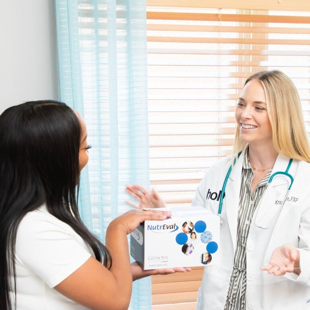 A healthcare professional in a white coat is gesturing while explaining something to a patient who is holding a testing kit.