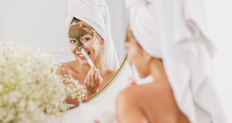 Woman in front of mirror applying algae skincare