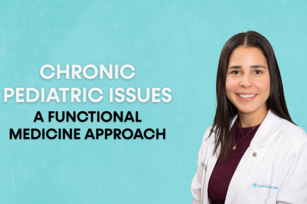 A woman wearing a white lab coat smiles directly at the camera against a light blue background.