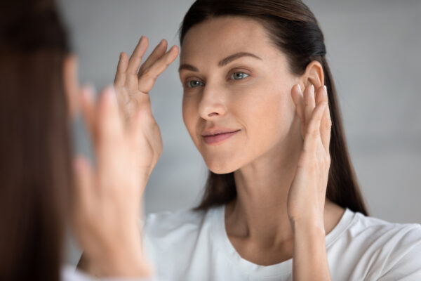 Woman inspecting clear skin
