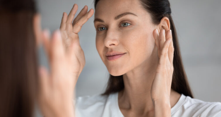 Woman inspecting clear skin