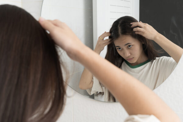 Young woman checking in bathroom mirror looking for hair loss