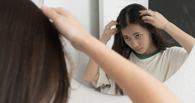 Young woman checking in bathroom mirror looking for hair loss