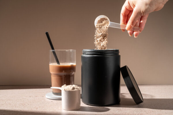 Scoop of creatine next to a glass of iced coffee