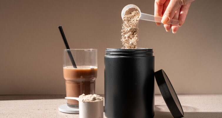 Scoop of creatine next to a glass of iced coffee